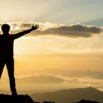 Pessoa em silhueta celebrando conquista pessoal ao nascer do sol - inspiração e autoconhecimento