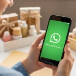 Empreendedora usando WhatsApp Business para vendas online no smartphone com produtos ao fundo